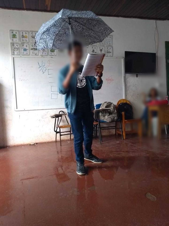 Estudante usa guarda-chuva durante aula por causa de goteiras em escola em Guaratinga. (Foto: Reroduo/Facebook)